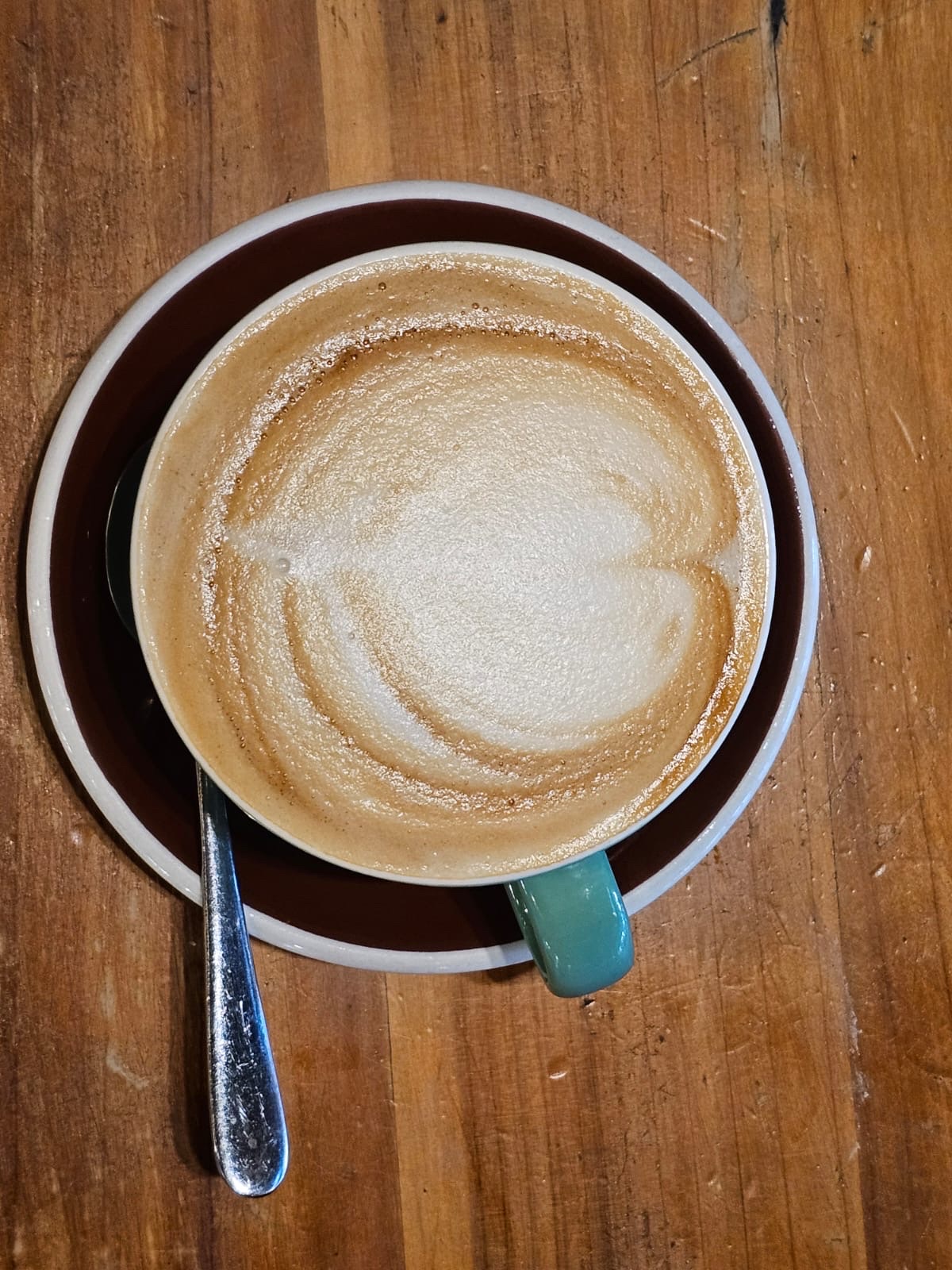 A flat white on a rustic wooden table